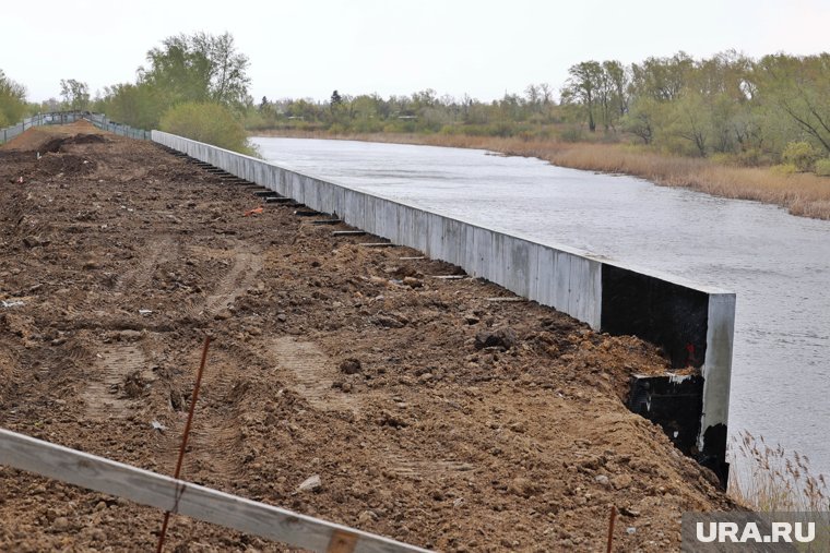 В Кургане дамбу возле незаконной высотки укрепили многометровой бетонной стеной. Фото, видео